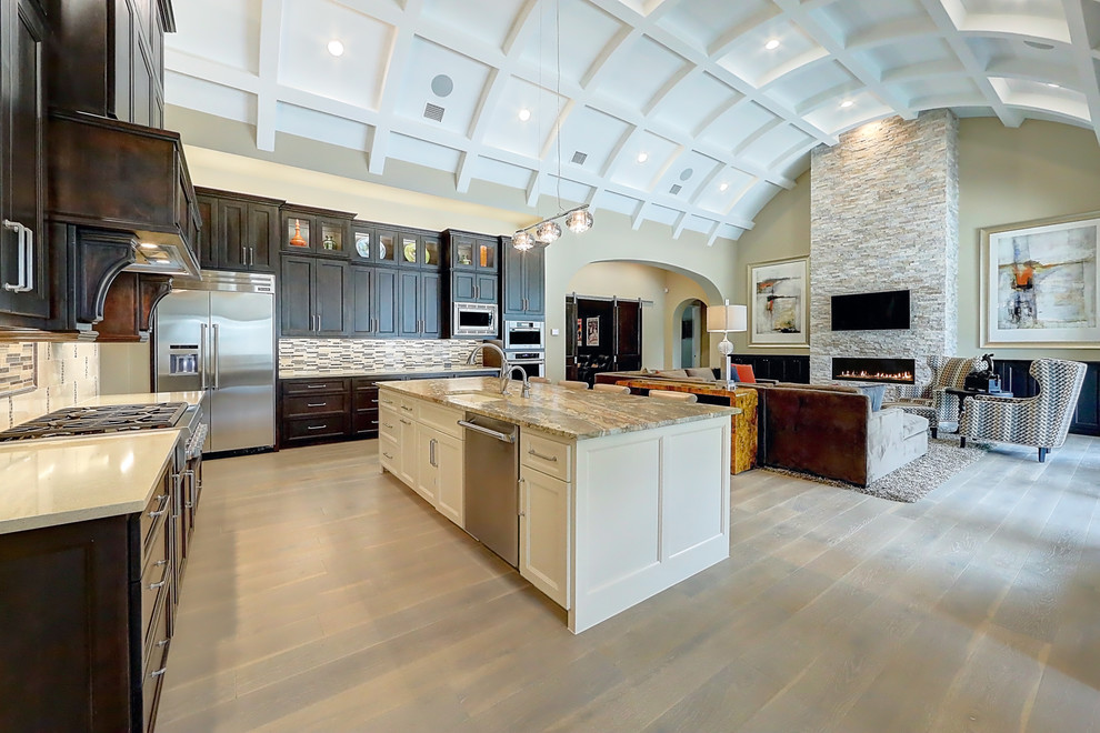 Large traditional l-shaped open plan kitchen in Austin with a submerged sink, shaker cabinets, white cabinets, engineered stone countertops, multi-coloured splashback, matchstick tiled splashback, stainless steel appliances, plywood flooring, an island and brown floors.