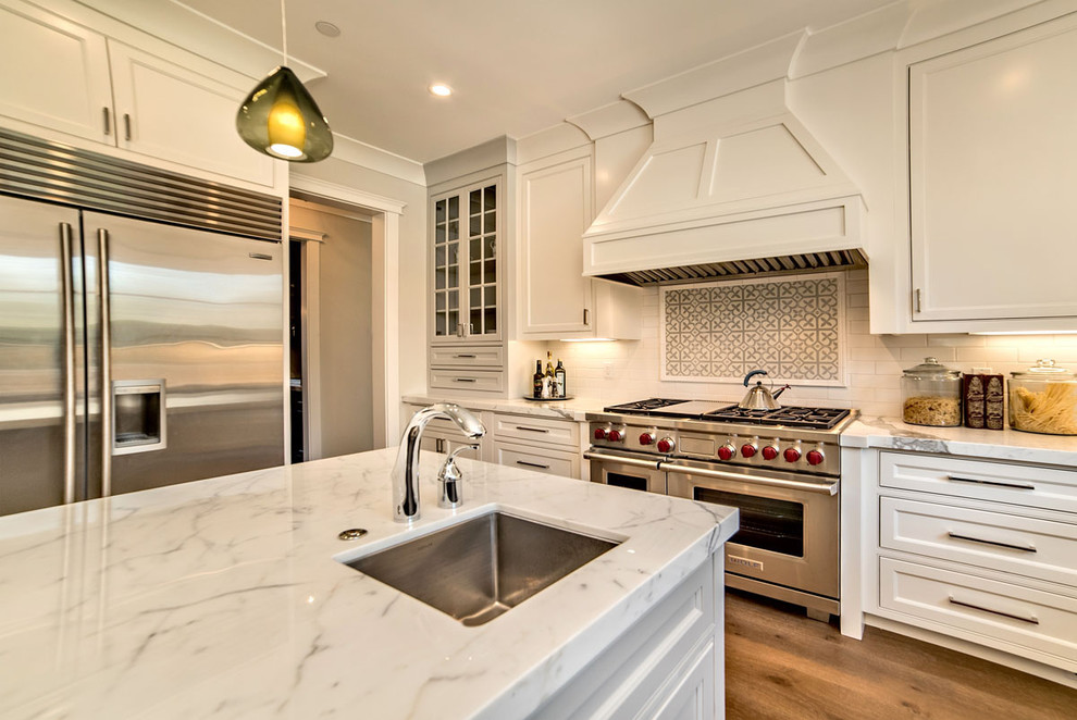 Example of a mid-sized classic medium tone wood floor eat-in kitchen design in San Francisco with a single-bowl sink, shaker cabinets, white cabinets, marble countertops, white backsplash, subway tile backsplash, stainless steel appliances and an island