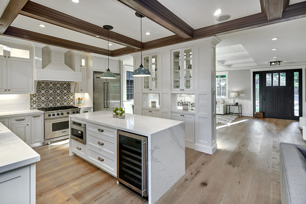 Example of a mid-sized cottage u-shaped light wood floor and gray floor open concept kitchen design in San Francisco with an undermount sink, shaker cabinets, white cabinets, quartz countertops, white backsplash, cement tile backsplash, stainless steel appliances, an island and white countertops