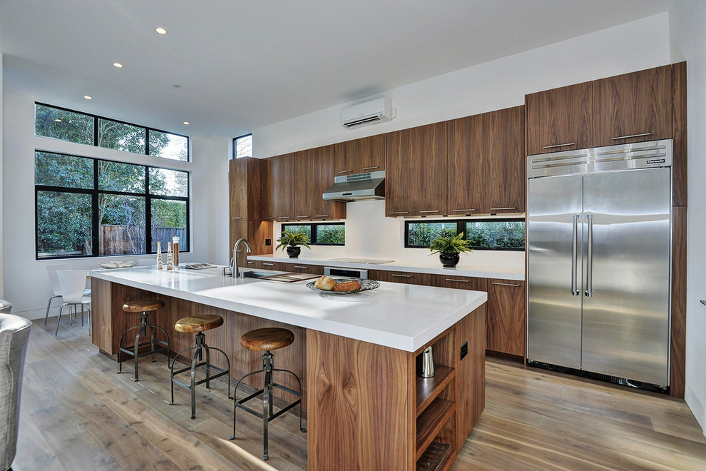 На фото: параллельная кухня-гостиная в современном стиле с плоскими фасадами, темными деревянными фасадами, белым фартуком и техникой из нержавеющей стали