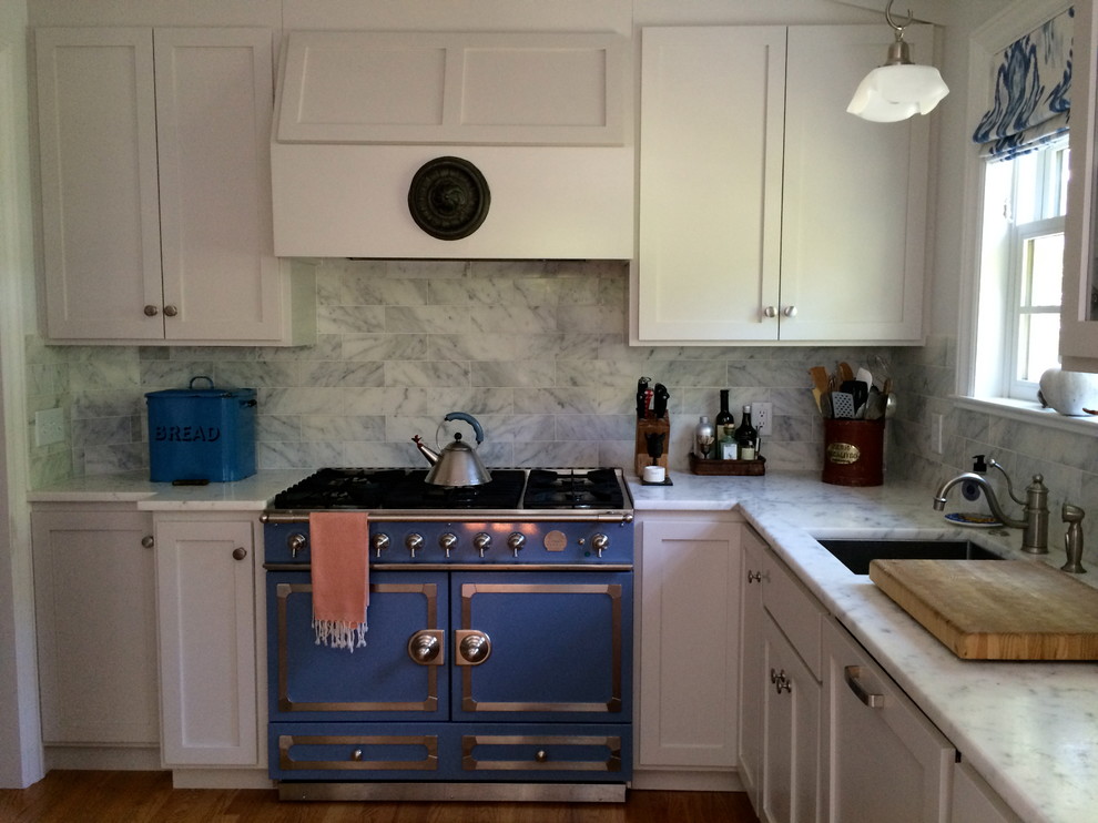 Example of a mid-sized transitional l-shaped medium tone wood floor enclosed kitchen design in San Francisco with no island, shaker cabinets, white cabinets, marble countertops, gray backsplash, stone tile backsplash, colored appliances and an undermount sink