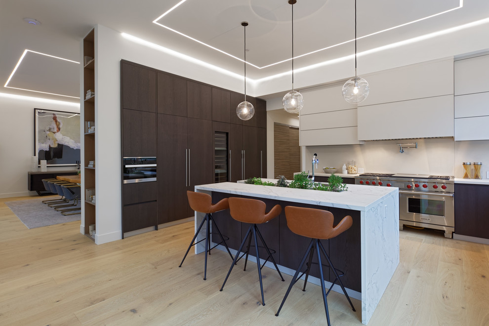 Example of a large minimalist l-shaped light wood floor and beige floor eat-in kitchen design in San Francisco with an undermount sink, flat-panel cabinets, marble countertops, beige backsplash, stone slab backsplash, an island, beige countertops, brown cabinets and paneled appliances