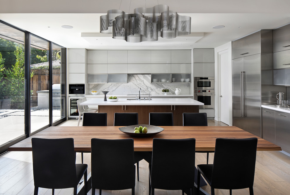 Medium sized contemporary l-shaped kitchen/diner in San Francisco with a submerged sink, flat-panel cabinets, grey cabinets, engineered stone countertops, white splashback, marble splashback, stainless steel appliances, light hardwood flooring, an island and white worktops.