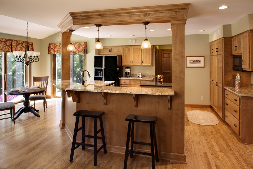 Example of a mid-sized classic u-shaped medium tone wood floor open concept kitchen design in Milwaukee with a double-bowl sink, shaker cabinets, medium tone wood cabinets, granite countertops, black appliances and an island