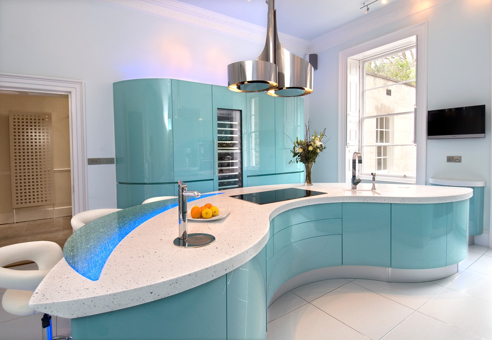 Large contemporary galley enclosed kitchen in London with an integrated sink, flat-panel cabinets, green cabinets, composite countertops, green splashback, glass sheet splashback, stainless steel appliances, ceramic flooring and an island.