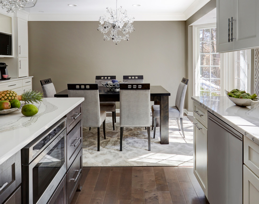 Example of a large trendy dark wood floor and brown floor enclosed kitchen design in Milwaukee with a single-bowl sink, shaker cabinets, white cabinets, quartz countertops, metallic backsplash, marble backsplash, stainless steel appliances, an island and white countertops