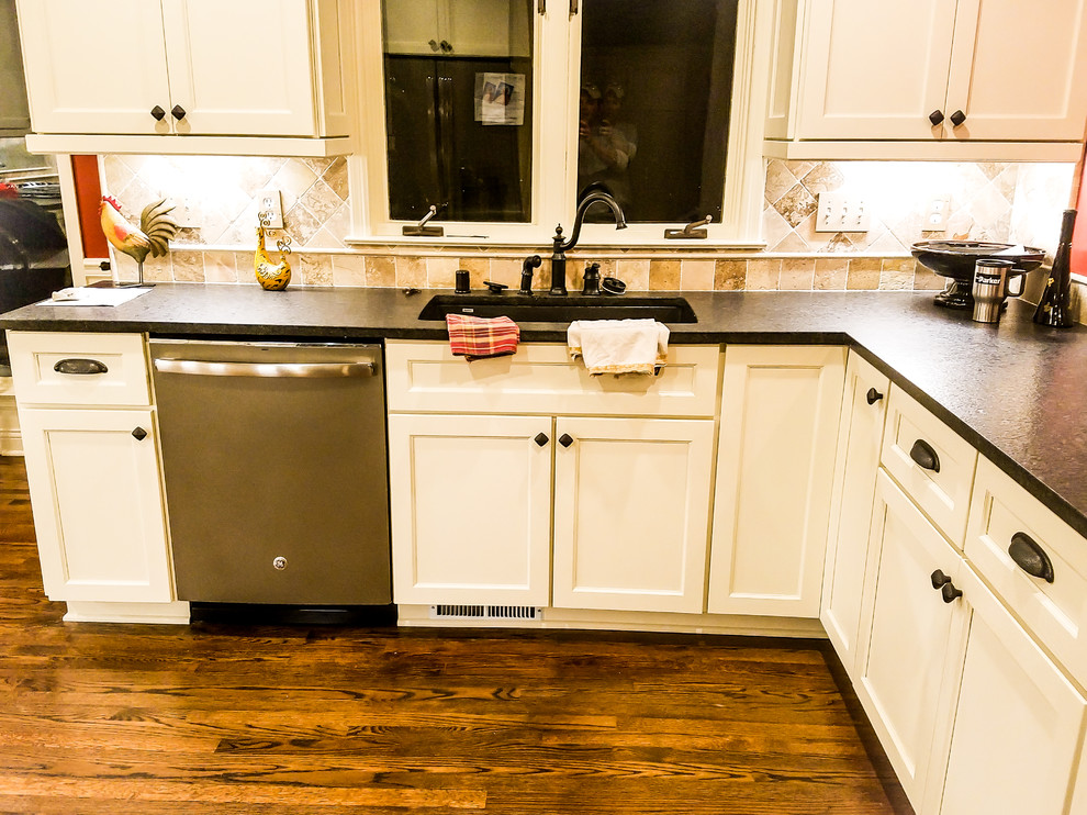 Bild på ett stort vintage kök, med en undermonterad diskho, luckor med infälld panel, vita skåp, granitbänkskiva, beige stänkskydd, stänkskydd i travertin, rostfria vitvaror, mörkt trägolv, en halv köksö och brunt golv