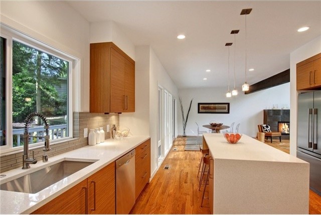 Inspiration for a large modern galley medium tone wood floor and brown floor enclosed kitchen remodel in Seattle with flat-panel cabinets, light wood cabinets, quartz countertops, gray backsplash, an island, a single-bowl sink, cement tile backsplash, stainless steel appliances and white countertops