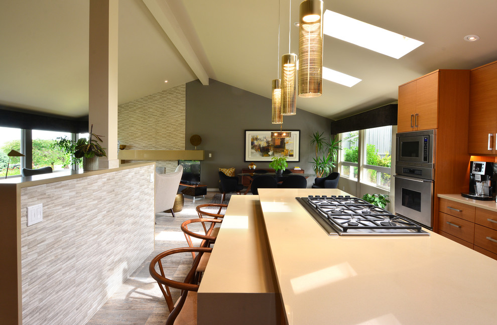 Inspiration for a large midcentury l-shaped open plan kitchen in Seattle with a single-bowl sink, flat-panel cabinets, light wood cabinets, engineered stone countertops, grey splashback, ceramic splashback, integrated appliances, travertine flooring, an island, grey floors and beige worktops.