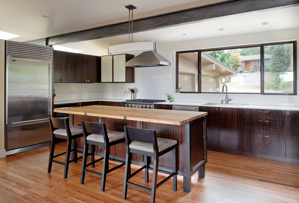 Diseño de cocina actual con armarios con paneles lisos, puertas de armario de madera en tonos medios y electrodomésticos de acero inoxidable