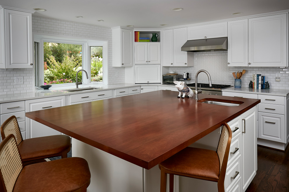 Enclosed kitchen - large traditional u-shaped dark wood floor and brown floor enclosed kitchen idea in Seattle with an undermount sink, raised-panel cabinets, white cabinets, wood countertops, white backsplash, subway tile backsplash, stainless steel appliances and an island
