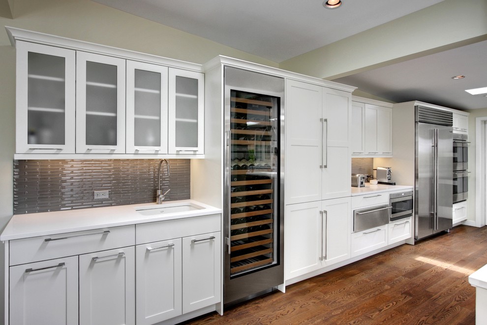 Example of a trendy eat-in kitchen design in Seattle with a farmhouse sink, recessed-panel cabinets, white cabinets, marble countertops, multicolored backsplash, stone tile backsplash and stainless steel appliances