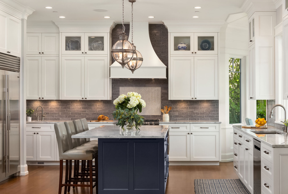 Design ideas for a large coastal kitchen in Seattle with a submerged sink, shaker cabinets, white cabinets, marble worktops, grey splashback, ceramic splashback, stainless steel appliances, medium hardwood flooring, an island, brown floors and grey worktops.
