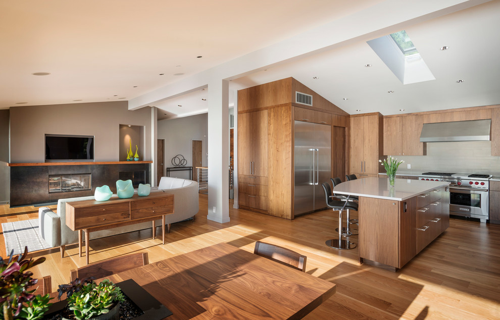 Offene Moderne Küche mit flächenbündigen Schrankfronten, hellbraunen Holzschränken und Küchengeräten aus Edelstahl in Seattle