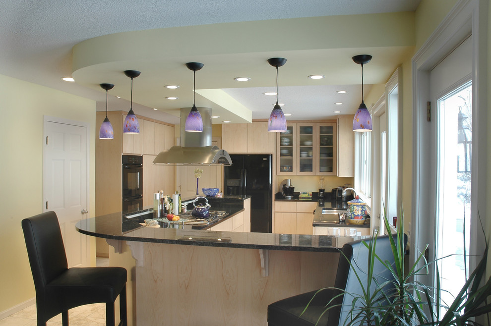 This is an example of a contemporary l-shaped kitchen/diner in Minneapolis with a submerged sink, flat-panel cabinets, light wood cabinets, granite worktops and black appliances.