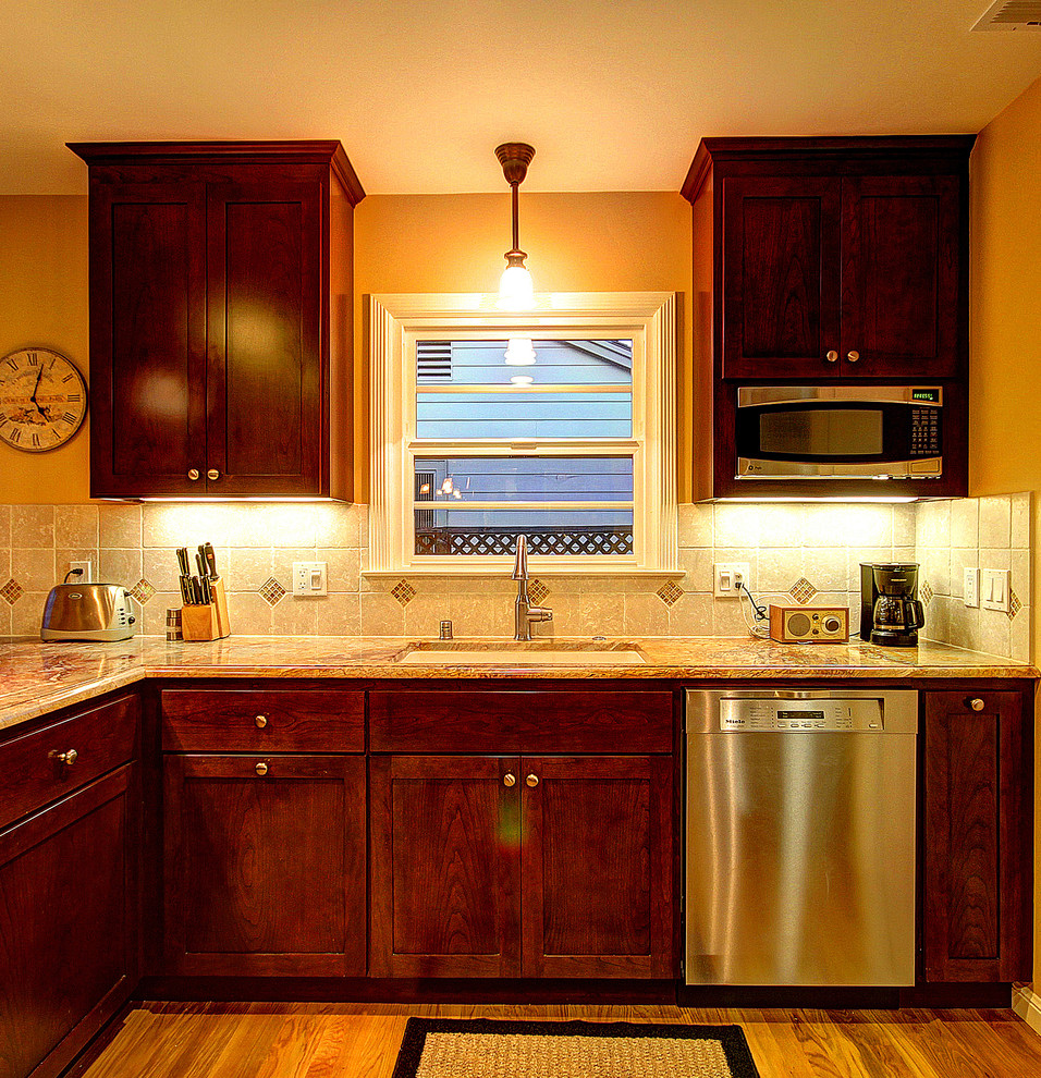 Foto på ett mellanstort vintage kök och matrum, med en undermonterad diskho, skåp i shakerstil, skåp i mörkt trä, granitbänkskiva, beige stänkskydd, rostfria vitvaror, mellanmörkt trägolv och en halv köksö