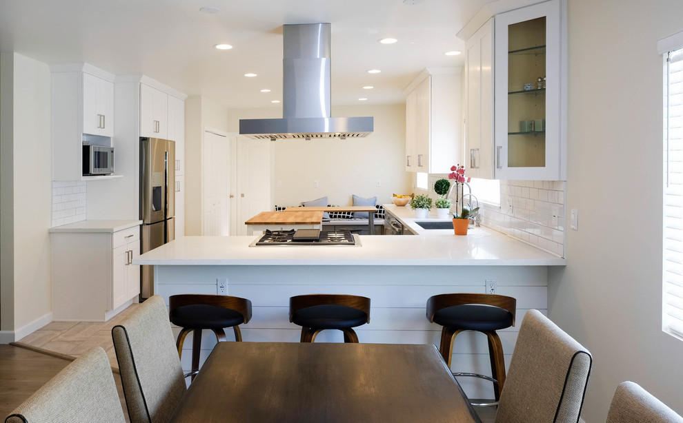 Photo of a large contemporary l-shaped kitchen/diner in Los Angeles with a built-in sink, shaker cabinets, white cabinets, engineered stone countertops, white splashback, ceramic splashback, stainless steel appliances, ceramic flooring, an island, pink floors and white worktops.