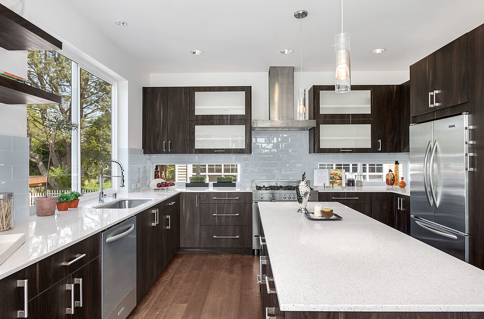 This is an example of a contemporary u-shaped kitchen in Seattle with flat-panel cabinets, dark wood cabinets, stainless steel appliances and an island.