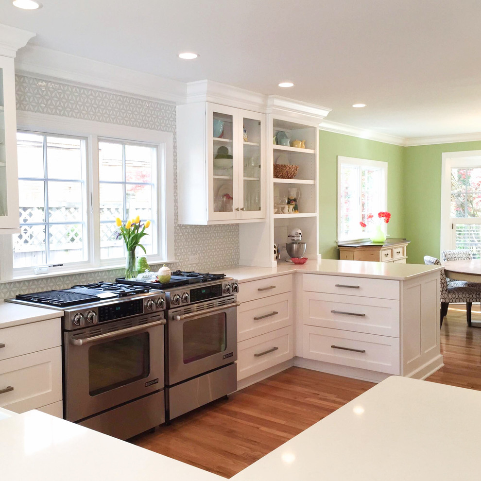 Example of a mid-sized transitional medium tone wood floor eat-in kitchen design in Indianapolis with shaker cabinets, white cabinets, a peninsula, quartzite countertops, gray backsplash and stainless steel appliances