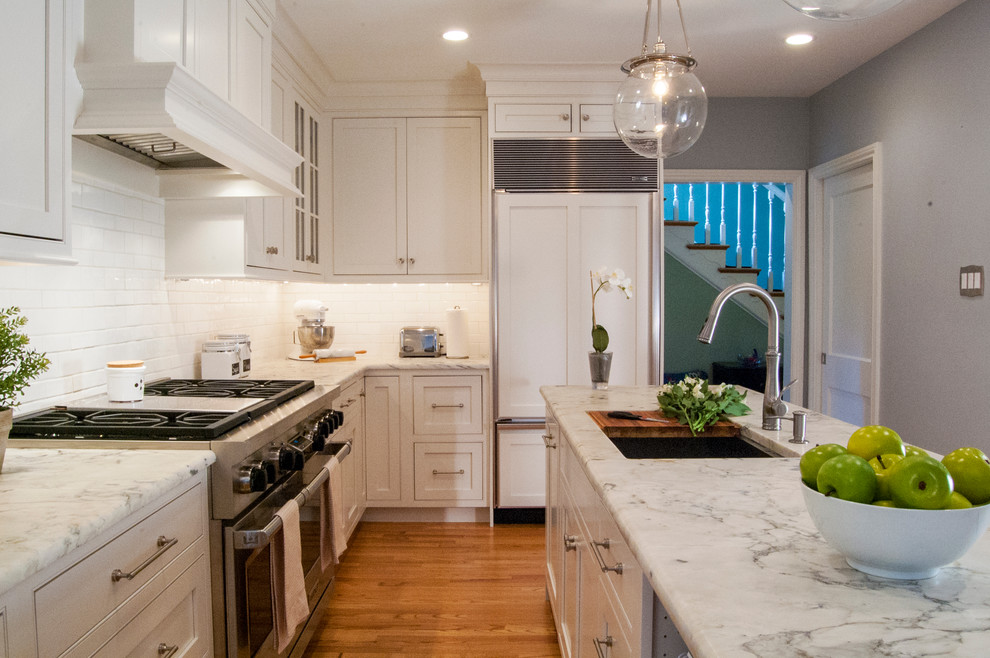 Eat-in kitchen - mid-sized transitional l-shaped medium tone wood floor eat-in kitchen idea in Philadelphia with an undermount sink, shaker cabinets, white cabinets, white backsplash, ceramic backsplash, stainless steel appliances, an island and quartzite countertops