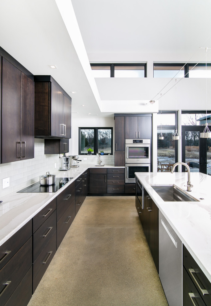 This is an example of a large modern l-shaped kitchen/diner in Detroit with a submerged sink, flat-panel cabinets, brown cabinets, quartz worktops, white splashback, glass tiled splashback, stainless steel appliances, concrete flooring, an island and white worktops.