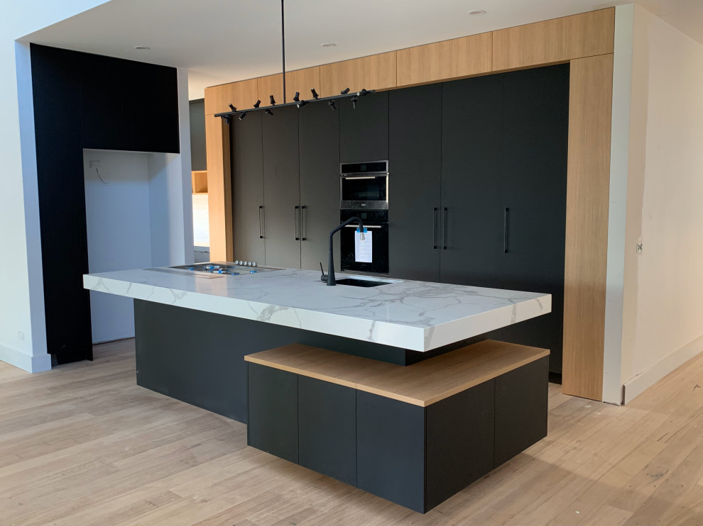 Modern single-wall kitchen/diner in Melbourne with recessed-panel cabinets, black cabinets, engineered stone countertops and an island.