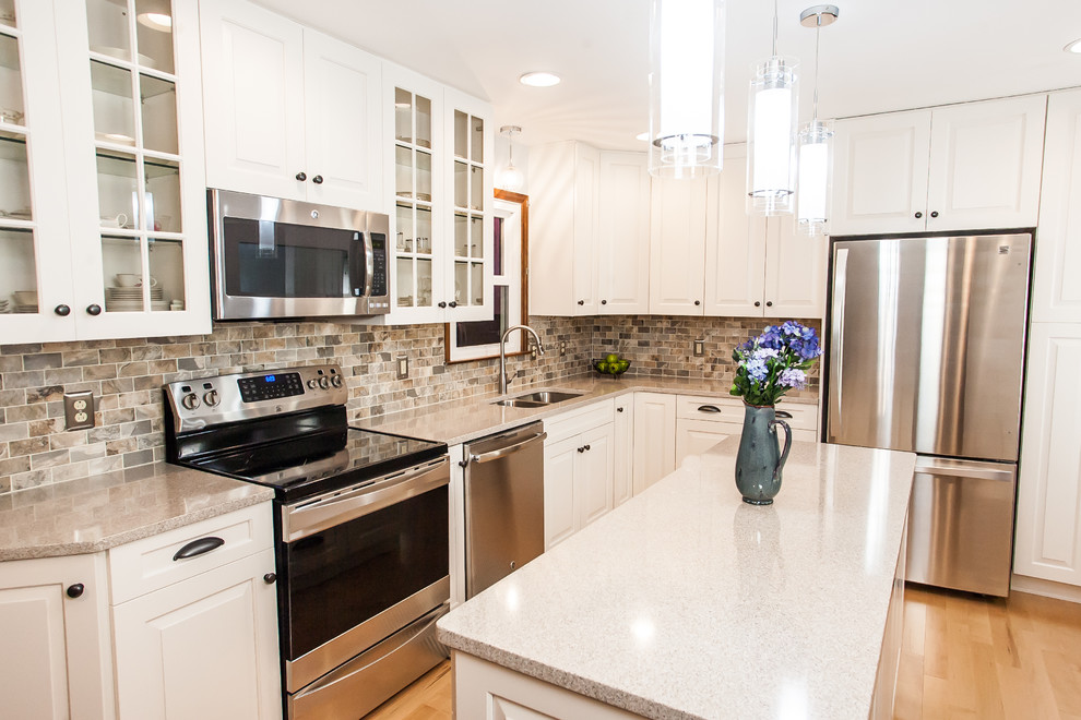 Eat-in kitchen - mid-sized traditional l-shaped light wood floor and beige floor eat-in kitchen idea in Baltimore with an undermount sink, raised-panel cabinets, white cabinets, quartz countertops, multicolored backsplash, mosaic tile backsplash, stainless steel appliances and an island