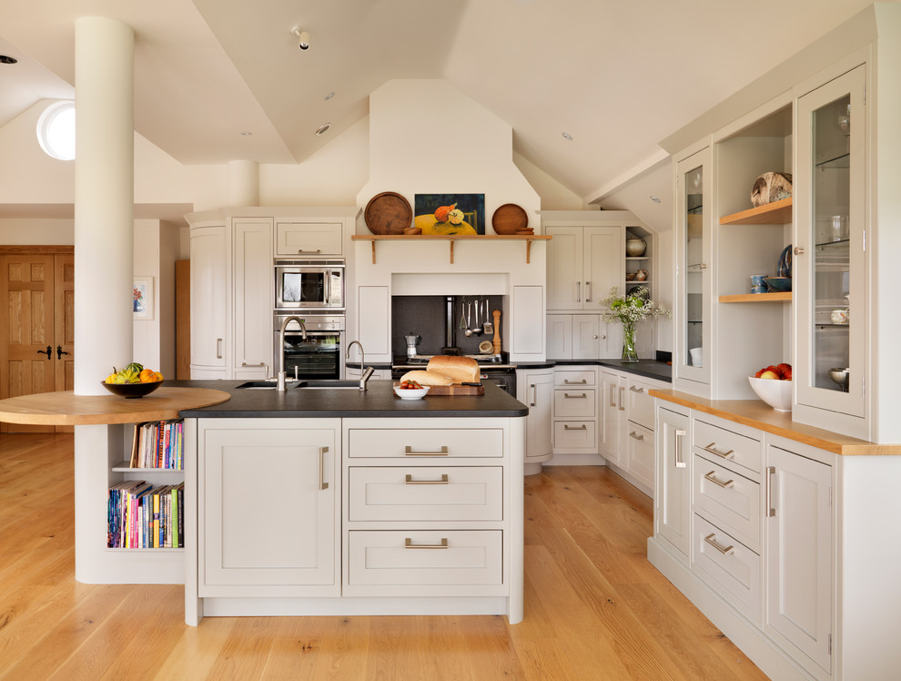 Inspiration for a medium sized traditional l-shaped open plan kitchen in Essex with a submerged sink, shaker cabinets, white cabinets, stainless steel appliances, medium hardwood flooring and an island.