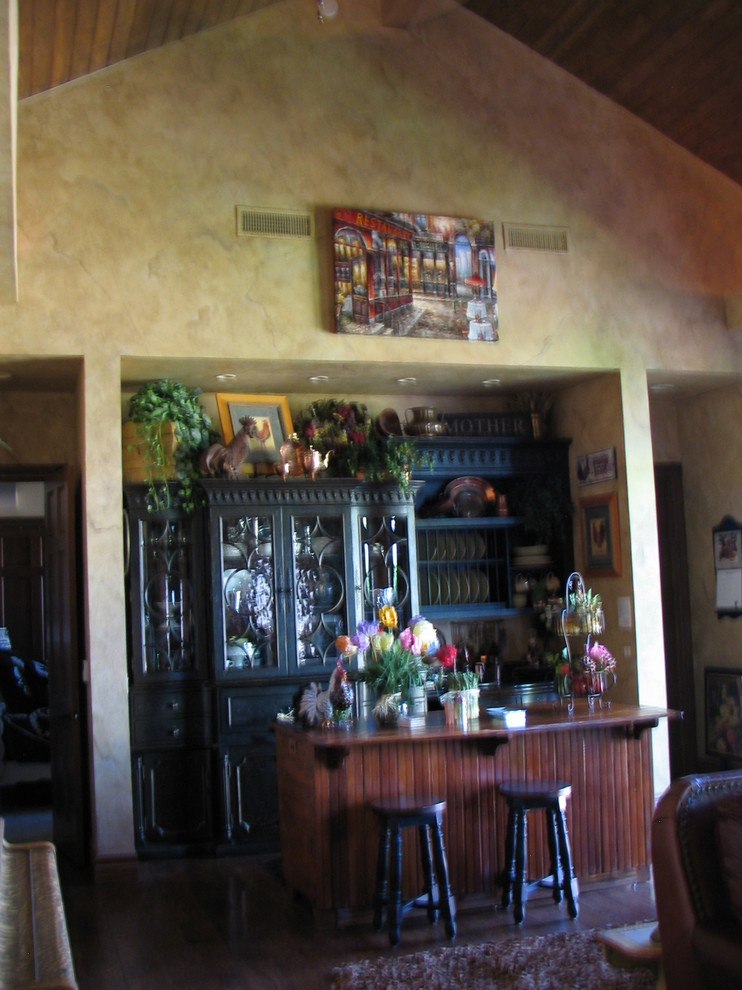 Diseño de cocina tradicional de tamaño medio abierta con armarios tipo vitrina, puertas de armario negras, encimera de madera, salpicadero beige, salpicadero de azulejos de piedra, suelo de madera oscura y una isla