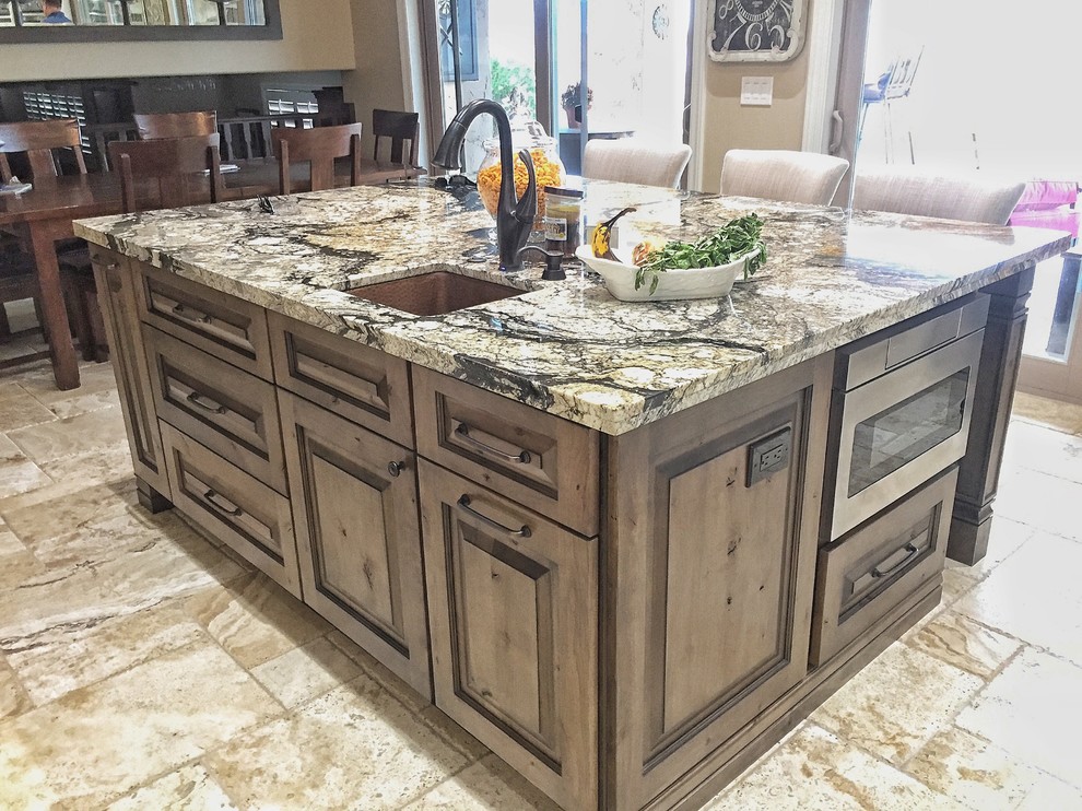 Inspiration for a large timeless l-shaped travertine floor and beige floor eat-in kitchen remodel in Phoenix with a farmhouse sink, raised-panel cabinets, white cabinets, granite countertops, gray backsplash, glass tile backsplash, stainless steel appliances, an island and multicolored countertops