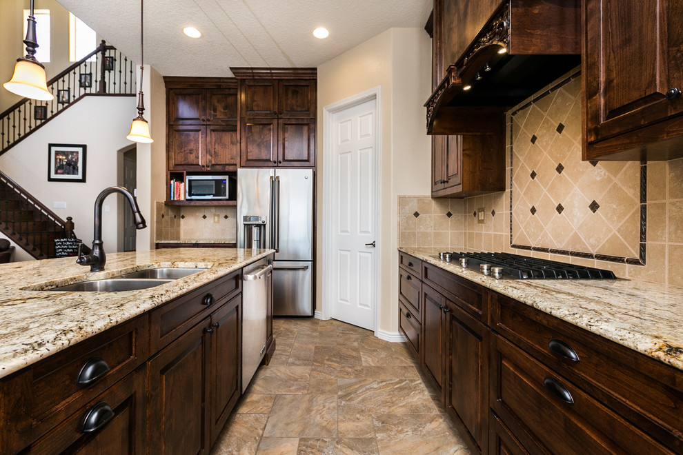Example of a large southwest l-shaped porcelain tile and brown floor eat-in kitchen design in Albuquerque with an undermount sink, raised-panel cabinets, dark wood cabinets, granite countertops, beige backsplash, ceramic backsplash, stainless steel appliances and an island