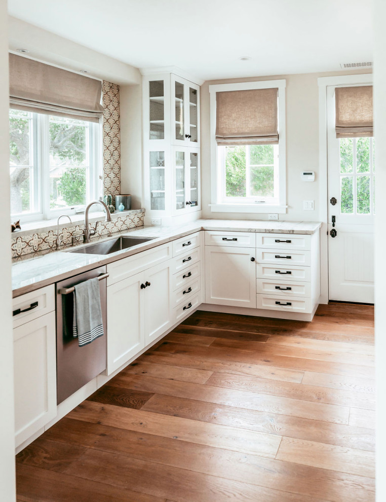 Foto på ett avskilt, mellanstort amerikanskt vit u-kök, med en undermonterad diskho, skåp i shakerstil, vita skåp, bänkskiva i kvartsit, flerfärgad stänkskydd, stänkskydd i mosaik, rostfria vitvaror och mellanmörkt trägolv