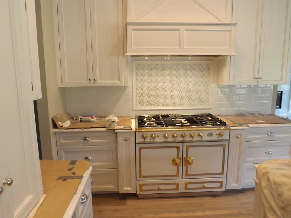 Exempel på ett stort klassiskt u-kök, med en rustik diskho, luckor med infälld panel, vita skåp, marmorbänkskiva, vitt stänkskydd, stänkskydd i tunnelbanekakel, rostfria vitvaror, mörkt trägolv och en köksö
