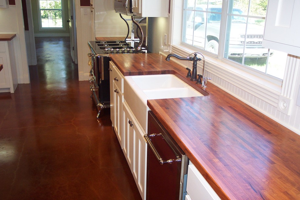オースティンにある広いトラディショナルスタイルのおしゃれなキッチン (エプロンフロントシンク、シェーカースタイル扉のキャビネット、白いキャビネット、木材カウンター、白いキッチンパネル、木材のキッチンパネル、シルバーの調理設備、コンクリートの床) の写真