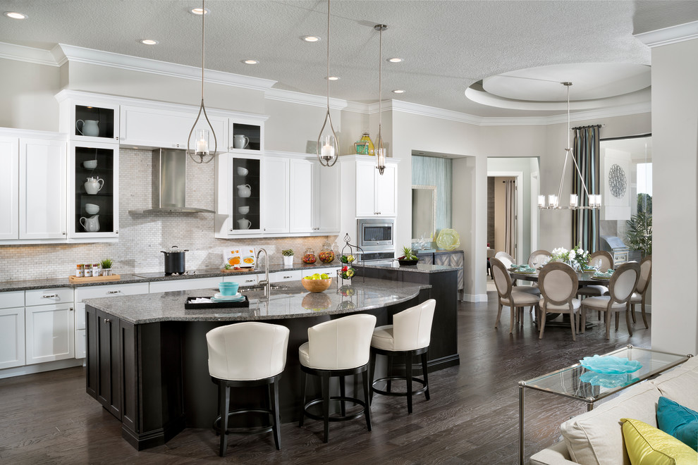 Example of a huge transitional l-shaped dark wood floor open concept kitchen design in Tampa with an undermount sink, raised-panel cabinets, white cabinets, granite countertops, beige backsplash, ceramic backsplash, stainless steel appliances and an island