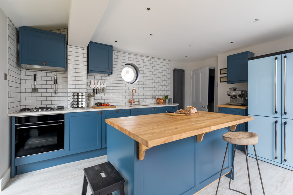 Inspiration for a contemporary kitchen in London with a submerged sink, shaker cabinets, blue cabinets, white splashback, metro tiled splashback, coloured appliances, an island, grey floors and white worktops.