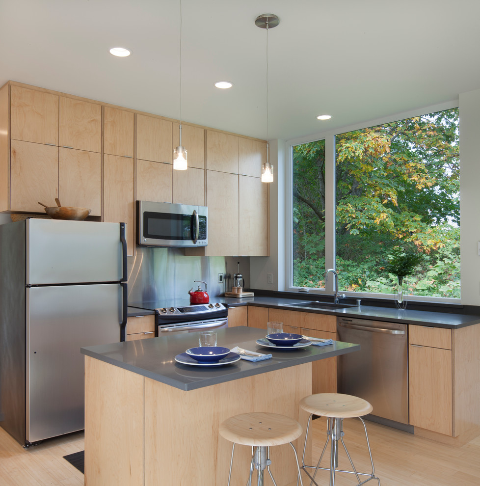 Moderne Küche in L-Form mit flächenbündigen Schrankfronten, hellen Holzschränken, Küchenrückwand in Metallic, Rückwand aus Metallfliesen, hellem Holzboden und Kücheninsel in Seattle