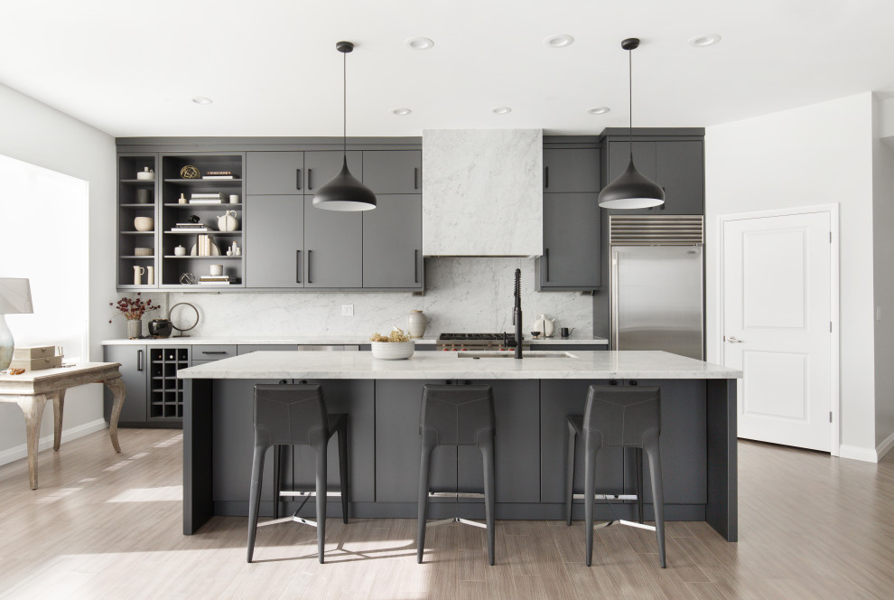 Inredning av ett modernt mellanstort grå grått kök, med en undermonterad diskho, släta luckor, blå skåp, marmorbänkskiva, grått stänkskydd, stänkskydd i marmor, rostfria vitvaror, ljust trägolv, en köksö och grått golv