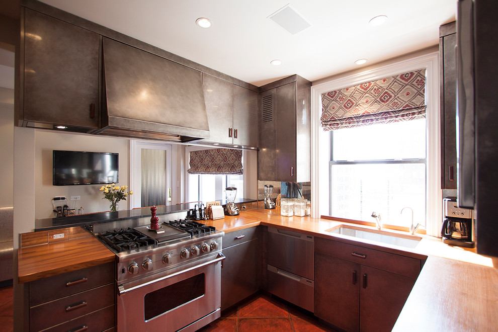 Exempel på ett modernt kök, med en undermonterad diskho, släta luckor, skåp i rostfritt stål, träbänkskiva, rostfria vitvaror och klinkergolv i porslin