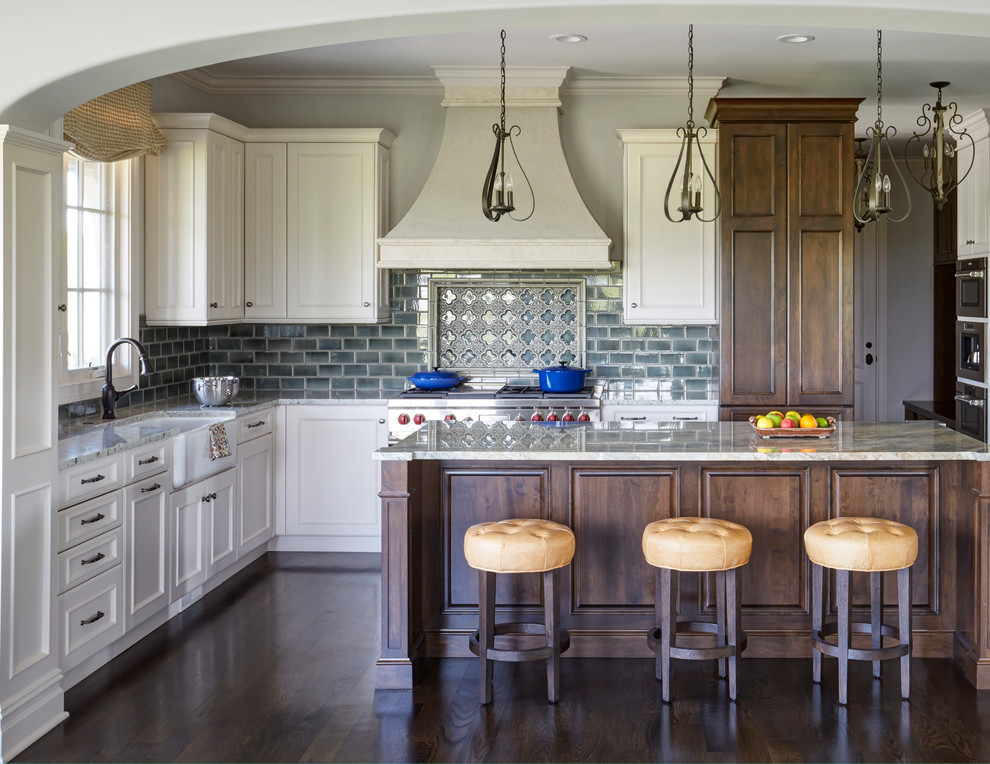 Inredning av ett stort grå grått kök, med luckor med infälld panel, vita skåp, en köksö, en rustik diskho, rostfria vitvaror, mörkt trägolv, brunt golv, granitbänkskiva, grönt stänkskydd och stänkskydd i keramik