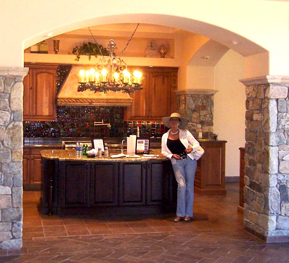 Inredning av ett medelhavsstil mellanstort kök, med en undermonterad diskho, luckor med upphöjd panel, skåp i mellenmörkt trä, granitbänkskiva, flerfärgad stänkskydd, integrerade vitvaror, klinkergolv i terrakotta och en köksö