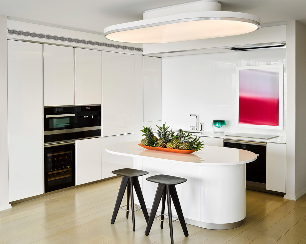 Moderne Küche in L-Form mit Unterbauwaschbecken, flächenbündigen Schrankfronten, weißen Schränken, hellem Holzboden, Kücheninsel, beigem Boden und weißer Arbeitsplatte in London
