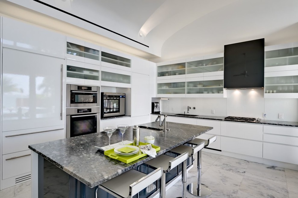 Modern inredning av ett kök, med en integrerad diskho, integrerade vitvaror, släta luckor, vita skåp och vitt stänkskydd