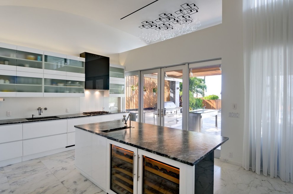 Moderne Küche mit integriertem Waschbecken, flächenbündigen Schrankfronten, weißen Schränken, Küchenrückwand in Weiß und Küchengeräten aus Edelstahl in Miami