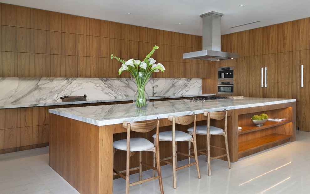 Zweizeilige Moderne Küche mit flächenbündigen Schrankfronten, hellbraunen Holzschränken, Küchenrückwand in Weiß, Küchengeräten aus Edelstahl, Kücheninsel und Rückwand aus Stein in Miami