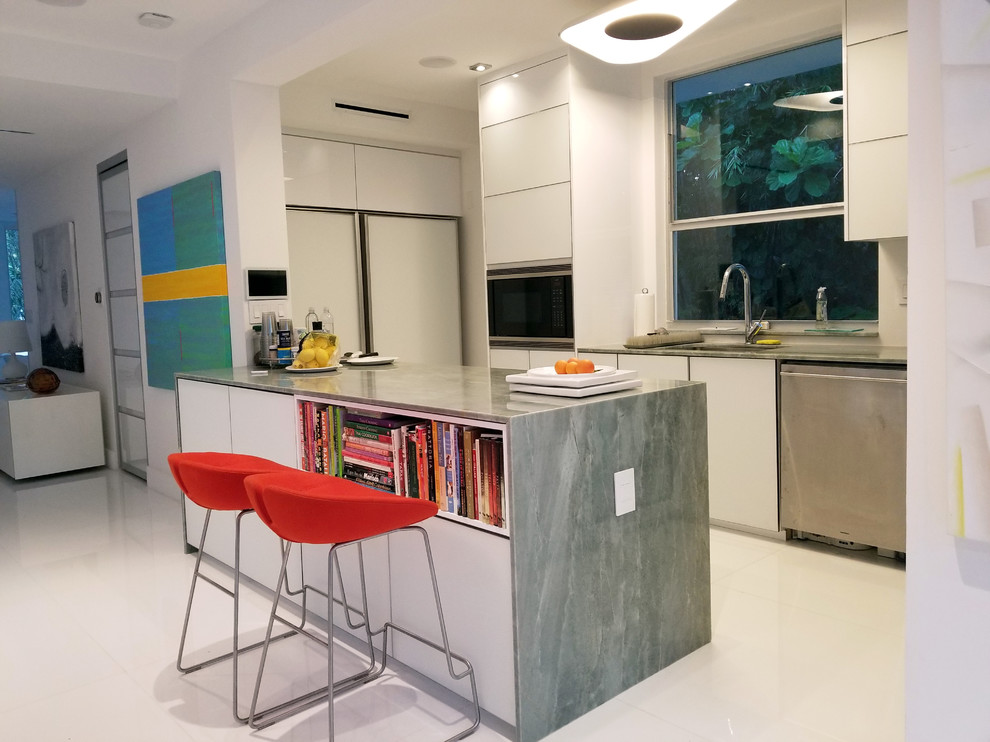 This is an example of a small modern u-shaped open plan kitchen in Miami with a submerged sink, glass-front cabinets, white cabinets, marble worktops, white splashback, glass sheet splashback, white appliances, marble flooring, an island, white floors and green worktops.
