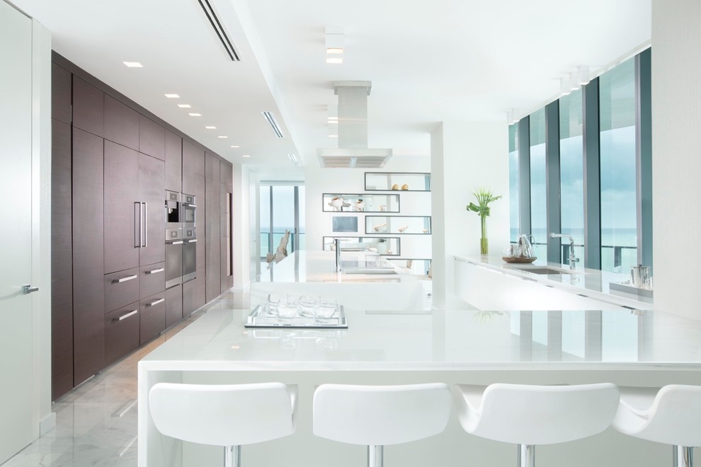 Kitchen pantry - huge contemporary l-shaped marble floor kitchen pantry idea in Miami with flat-panel cabinets, dark wood cabinets, marble countertops, white backsplash, stone slab backsplash, paneled appliances, an island and an undermount sink