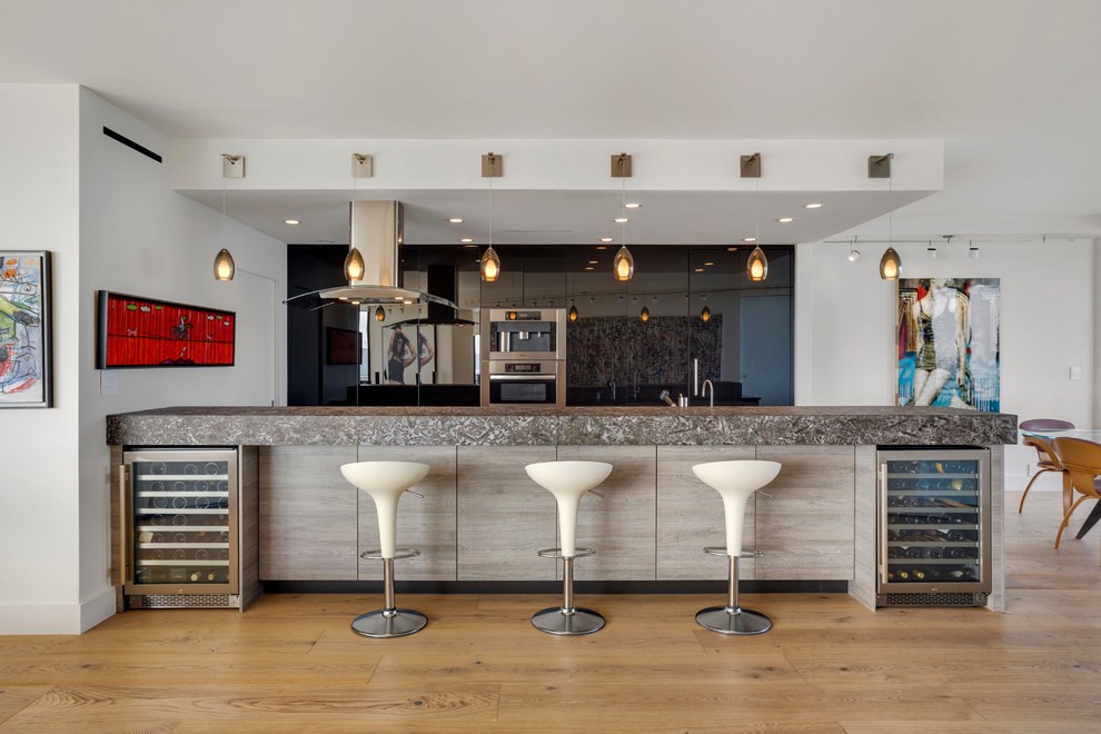 ニューヨークにある高級な中くらいなコンテンポラリースタイルのおしゃれなキッチン (フラットパネル扉のキャビネット、黒いキャビネット、御影石カウンター、シルバーの調理設備、淡色無垢フローリング) の写真