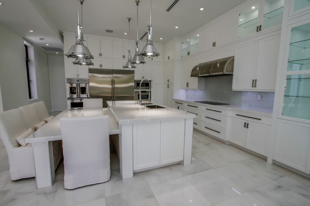 Idéer för att renovera ett stort funkis l-kök, med en undermonterad diskho, skåp i shakerstil, vita skåp, bänkskiva i kvarts, grått stänkskydd, stänkskydd i glaskakel, rostfria vitvaror, marmorgolv, en köksö och vitt golv