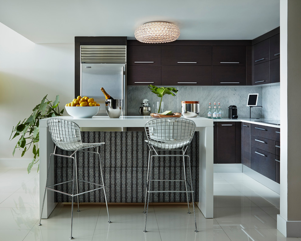Small trendy l-shaped open concept kitchen photo in Miami with flat-panel cabinets, dark wood cabinets, marble countertops, gray backsplash, stone slab backsplash, stainless steel appliances and an island
